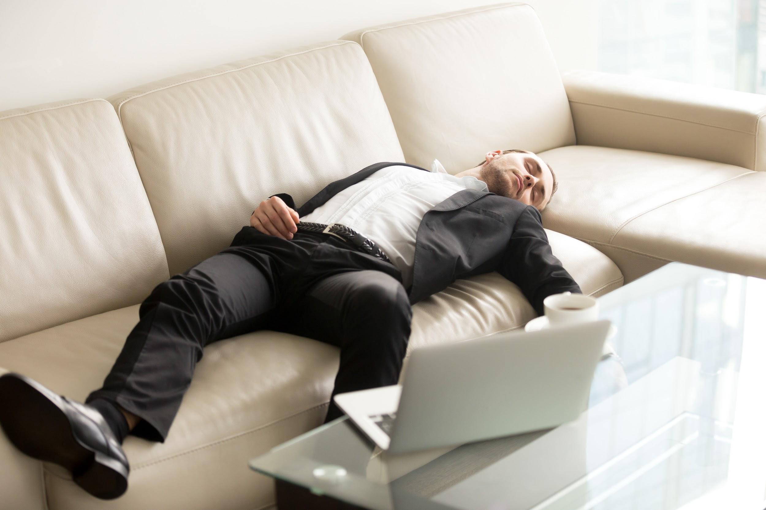 Man laying on the sofa near laptop